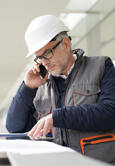 Ein Mann mit einem Schutzhelm spricht am Handy.