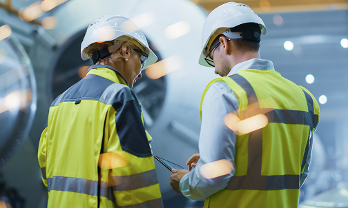 Zwei Personen in Sicherheitswesten betrachten aufmerksam etwas.