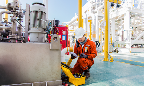 Ein Mann in einem orangefarbenen Sicherheitsanzug arbeitet an einer Maschine.