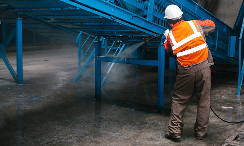 Ein Mann mit einem Schutzhelm steht vor einem Bedienfeld.
